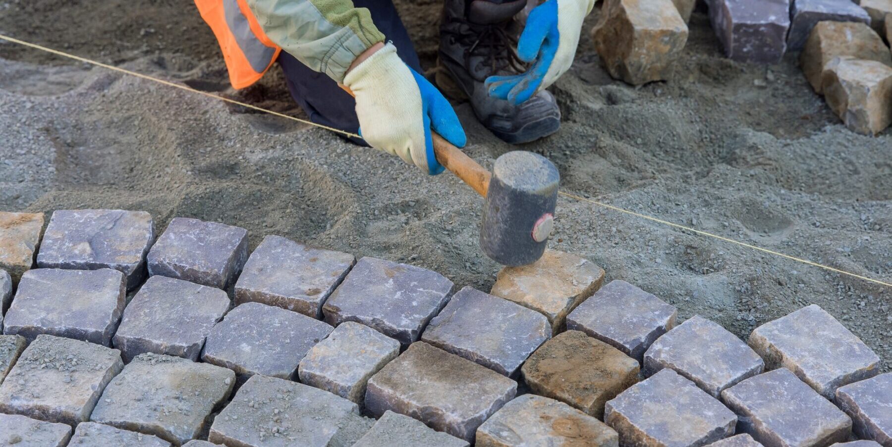 The worker were busy paving the sidewalk with granite stones.